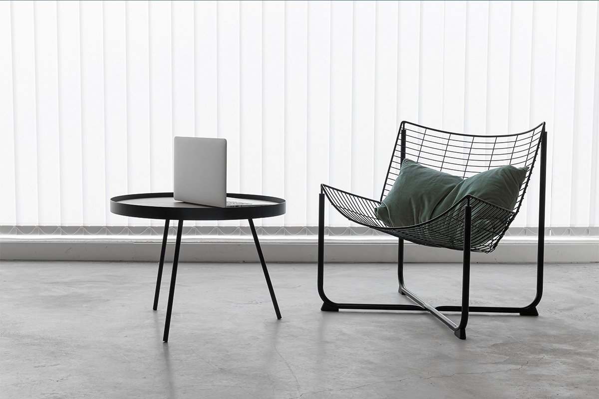 Image of a room with a rest chair, table, and laptop, highlighting the transformative power of furniture photo editing services.